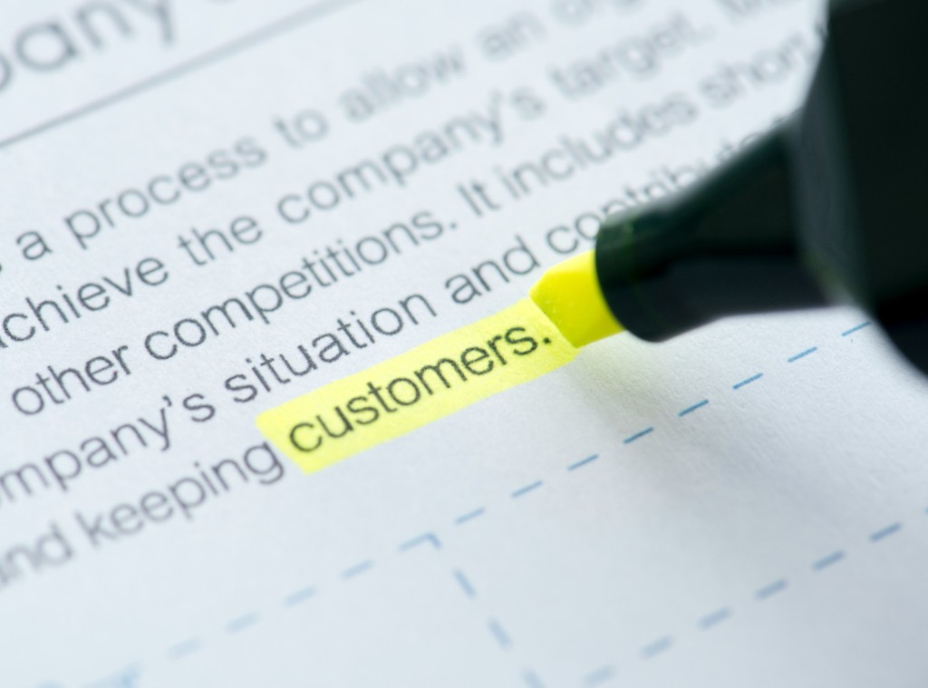 英文のマーケティング文書で「customers」という語句に蛍光ペンで線を引いている写真。顧客を起点にマーケティングを読むイメージ